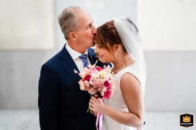 In Trieste, Italy, the loving father of the bride leans in closely to tenderly kiss his daughter upon her forehead before the ceremony.